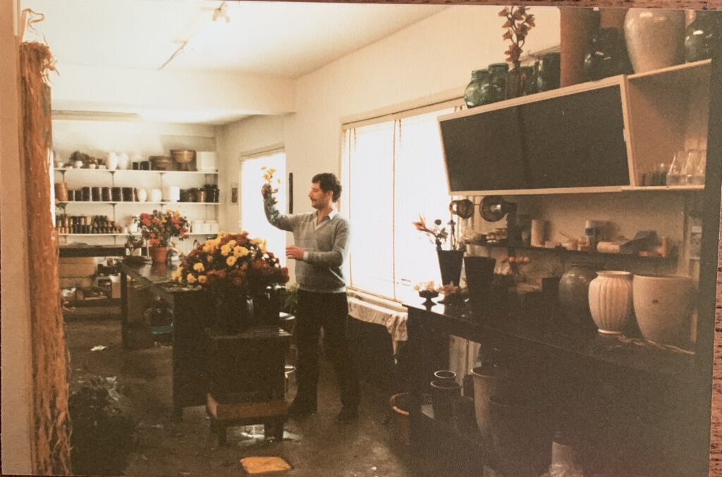 a photo of the den haag flower shop regina flowers from a very long time ago, a man is standing on a light yellow tinted photo with flowers at work